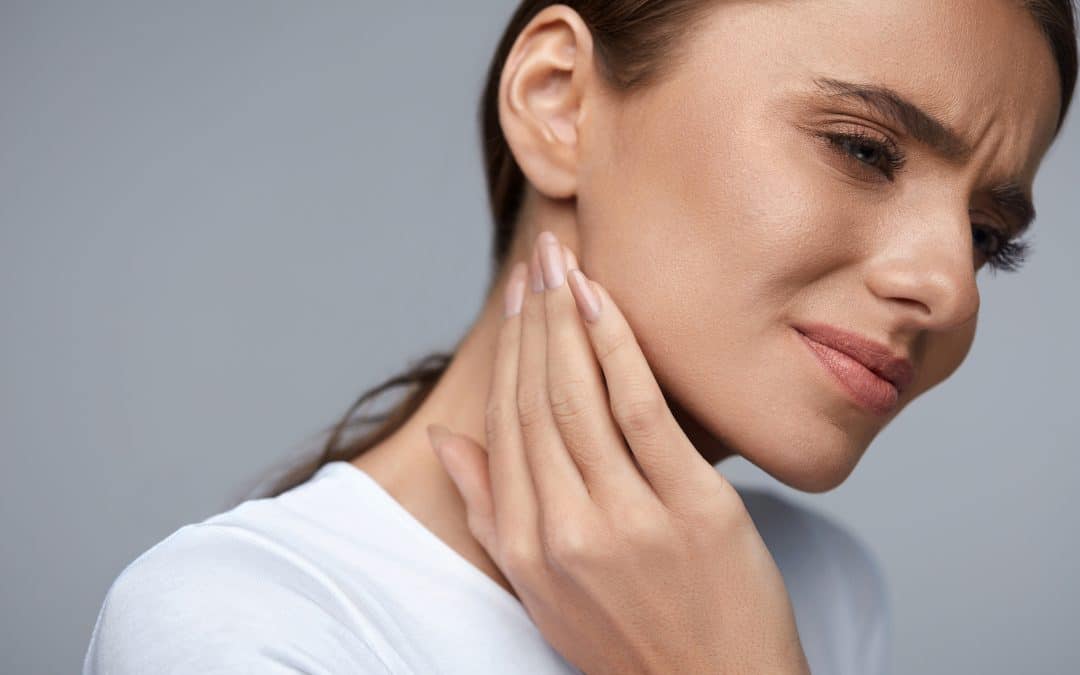 woman holding jaw in pain - iHeart Dental